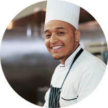 Young man wearing a chef's hat with a short beard and an apron